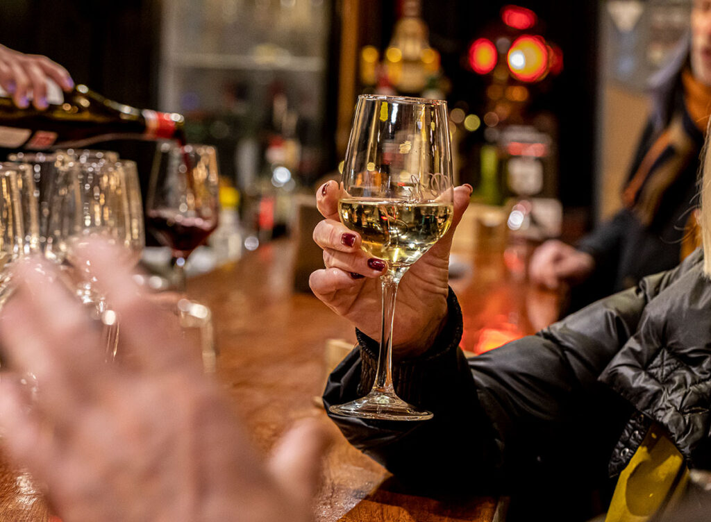 Mano de mujer sosteniendo copa de vino blanco